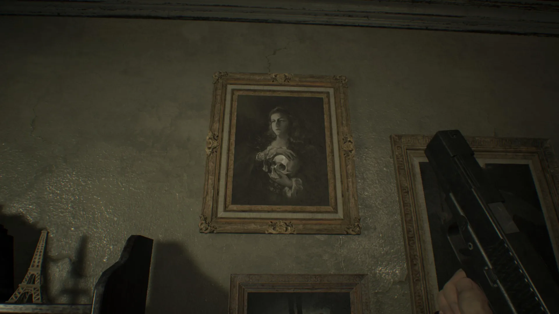 L'image est une capture d'écran du jeu Resident Evil 7. La caméra, qui adopte le point de vue du personnage joueur, nous montre un mur auquel est accrochée une gravure pastichant une oeuvre de l'artiste James Sant.